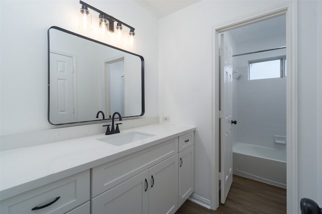 bathroom featuring wood-type flooring, tiled shower / bath, and vanity