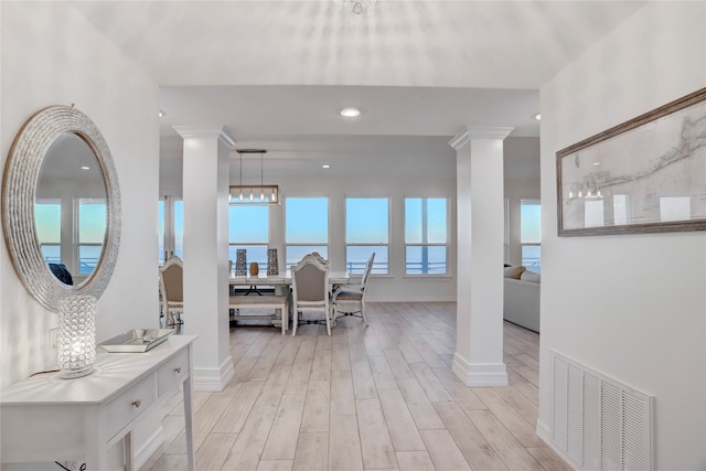 interior space featuring light wood-type flooring, decorative columns, and plenty of natural light