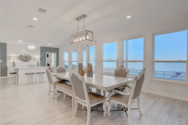 dining area with a notable chandelier, a water view, light hardwood / wood-style floors, and french doors