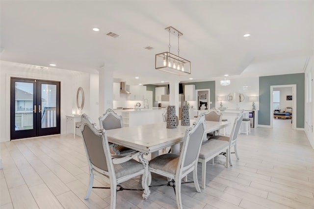 dining space with french doors, light hardwood / wood-style flooring, and sink