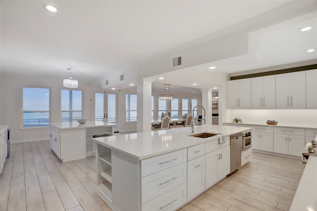 kitchen with an island with sink, light hardwood / wood-style flooring, and decorative light fixtures