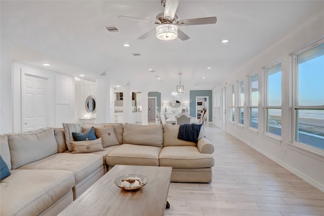 living room featuring ornamental molding, light wood-type flooring, and ceiling fan