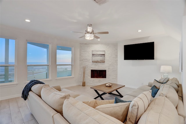 living room with a water view, ceiling fan, light hardwood / wood-style floors, and a fireplace