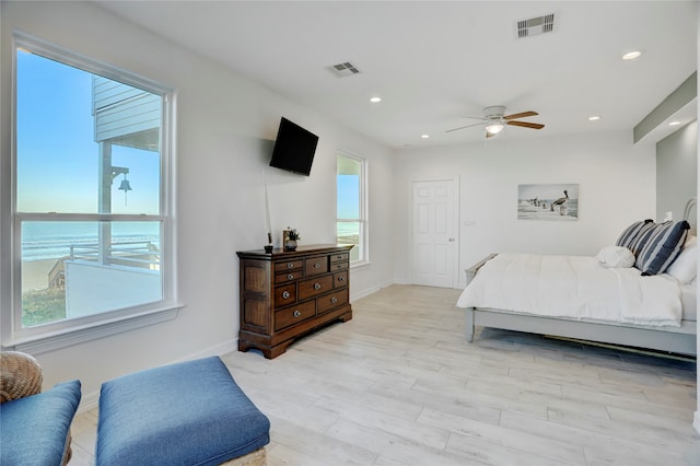 bedroom featuring a water view, multiple windows, and ceiling fan