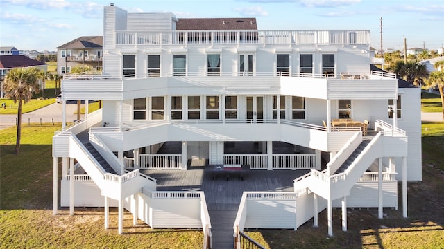 back of property with a lawn, a balcony, and a wooden deck