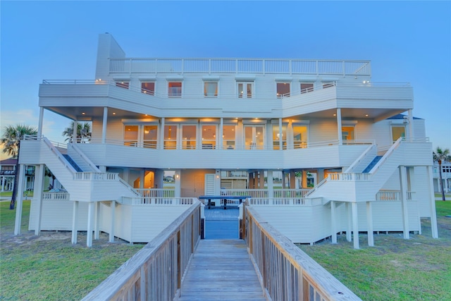 rear view of property featuring a balcony and a yard