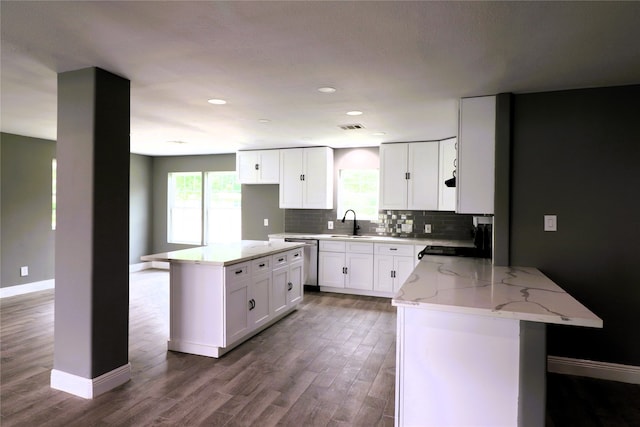 kitchen featuring light stone counters, white cabinets, hardwood / wood-style flooring, a center island, and black range oven