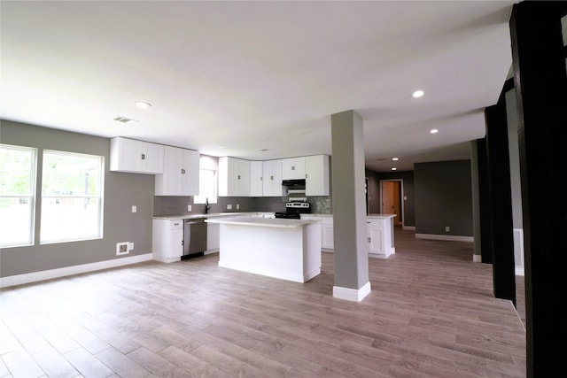 kitchen with white cabinets, appliances with stainless steel finishes, light hardwood / wood-style flooring, and a kitchen island