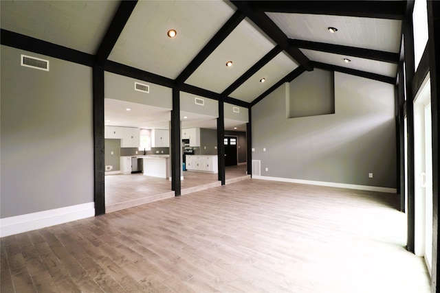 unfurnished living room featuring light hardwood / wood-style floors, high vaulted ceiling, and beamed ceiling