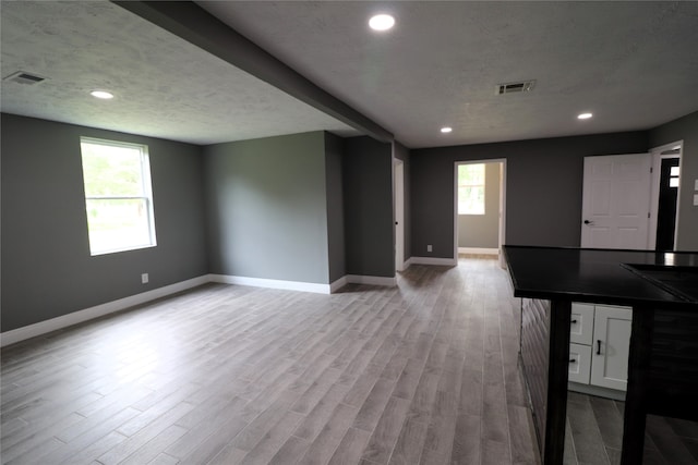 unfurnished living room featuring a textured ceiling, light hardwood / wood-style flooring, and a wealth of natural light