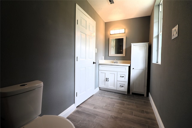 bathroom with hardwood / wood-style flooring, vanity, and toilet