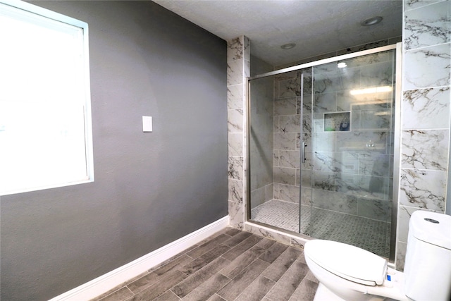 bathroom featuring toilet, an enclosed shower, and a wealth of natural light