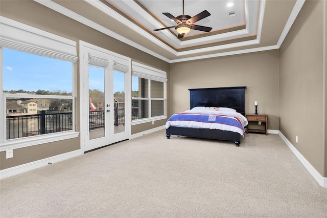 carpeted bedroom featuring ceiling fan, a tray ceiling, crown molding, access to exterior, and french doors