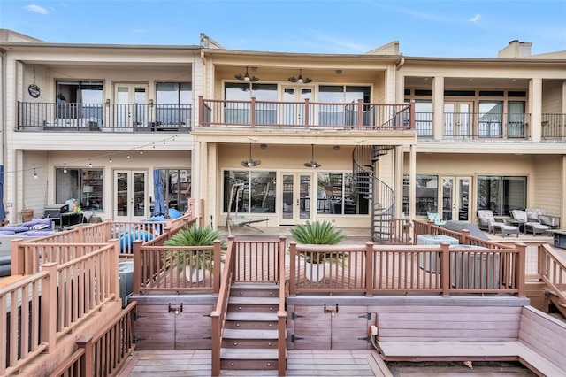 back of property with french doors, a balcony, and a wooden deck