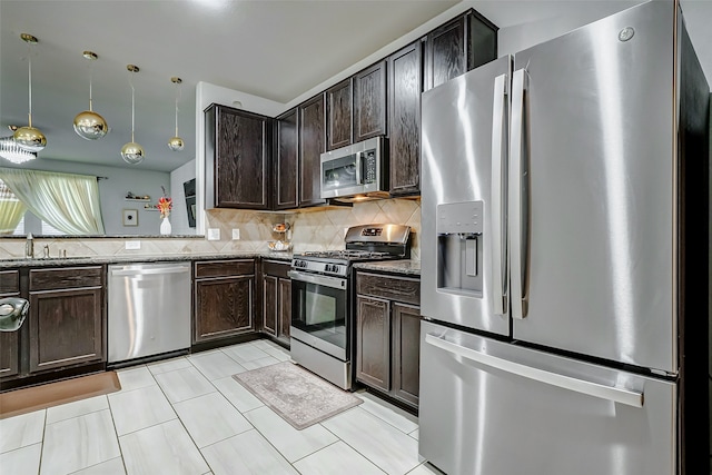 kitchen featuring sink, stainless steel appliances, light stone counters, backsplash, and decorative light fixtures