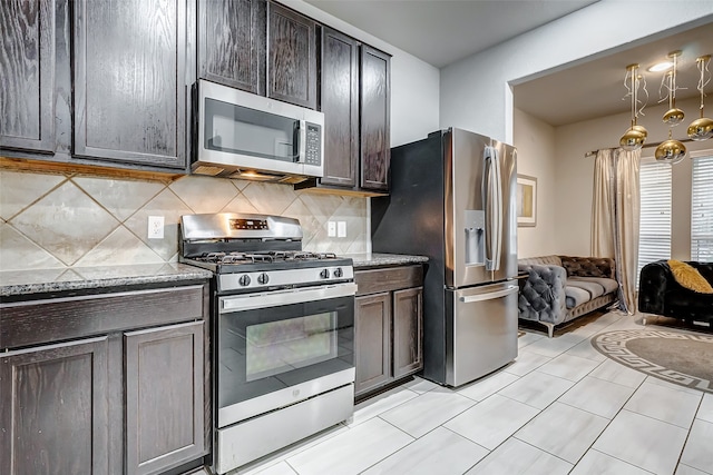 kitchen featuring appliances with stainless steel finishes, tasteful backsplash, dark brown cabinets, and stone countertops