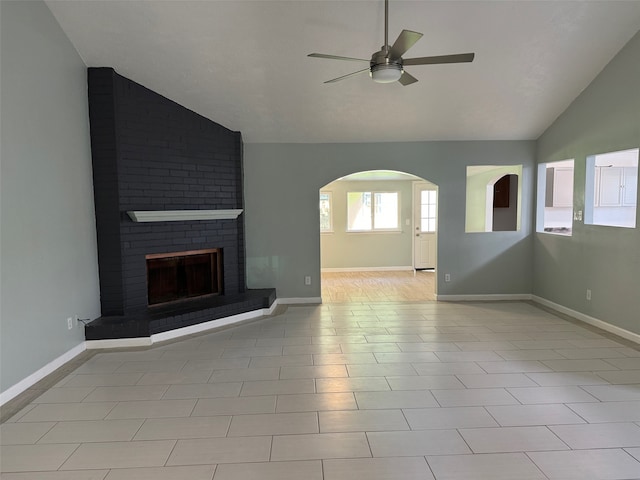 unfurnished living room with ceiling fan, lofted ceiling, a fireplace, and light tile patterned floors