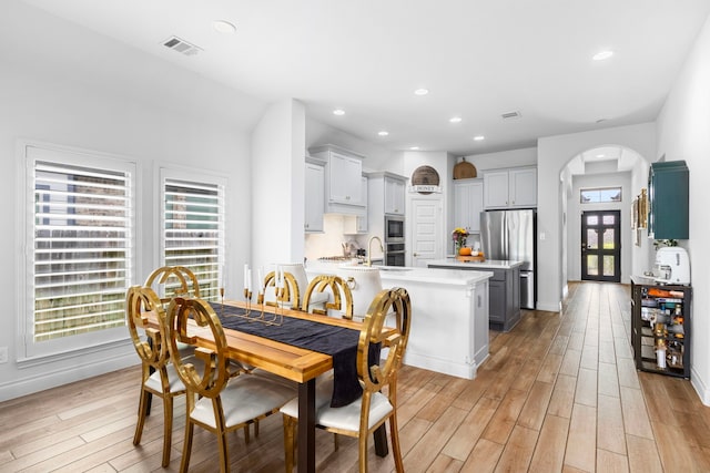 dining area with beverage cooler, light hardwood / wood-style floors, and sink