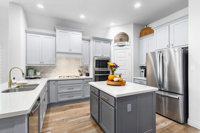 kitchen featuring gray cabinetry, sink, light hardwood / wood-style flooring, and stainless steel appliances