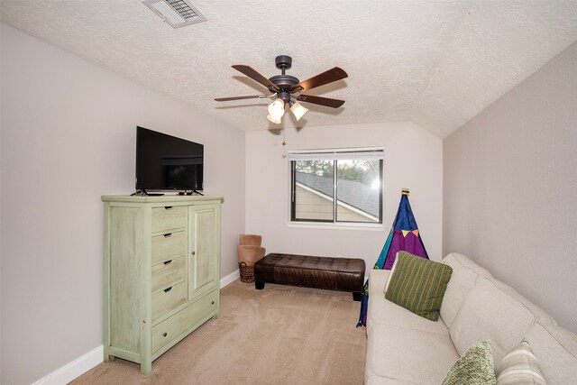 living area with ceiling fan, light colored carpet, and a textured ceiling