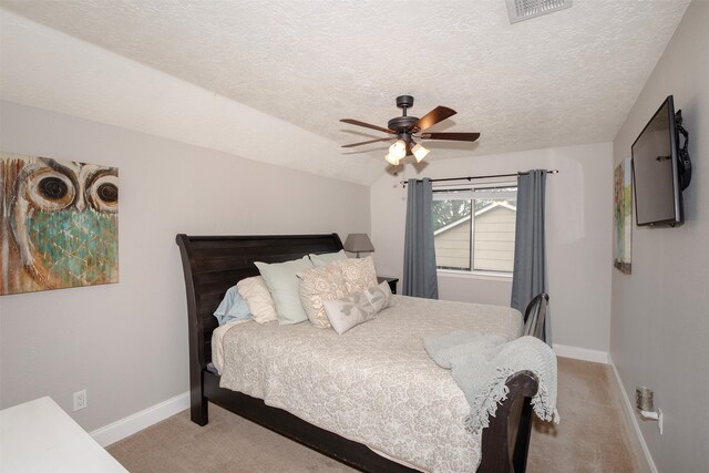 bedroom with a textured ceiling, ceiling fan, and light carpet