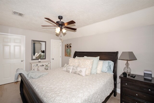 bedroom with a textured ceiling, light colored carpet, and ceiling fan