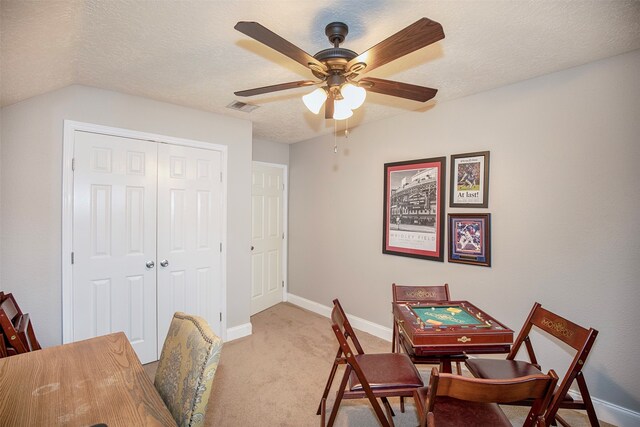 dining space featuring a textured ceiling, ceiling fan, lofted ceiling, and light carpet