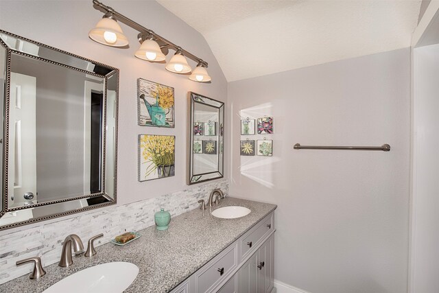 bathroom with vanity, backsplash, and vaulted ceiling