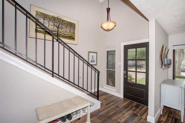 entryway featuring vaulted ceiling, dark wood-type flooring, and a textured ceiling