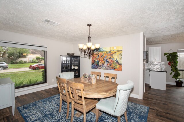 dining area with dark hardwood / wood-style flooring, a textured ceiling, and an inviting chandelier