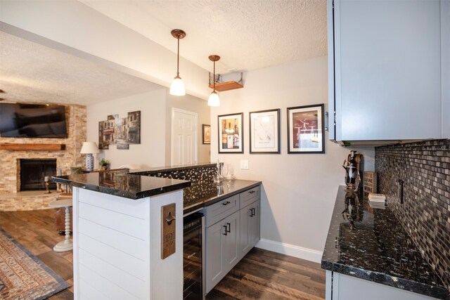 kitchen with kitchen peninsula, pendant lighting, a textured ceiling, and a fireplace