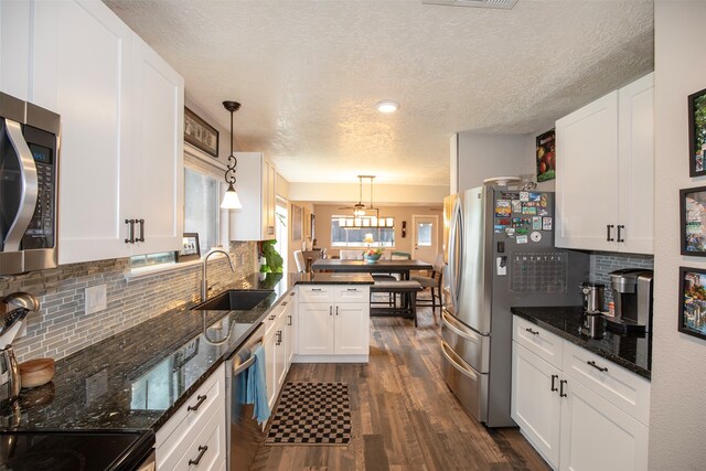 kitchen featuring dark hardwood / wood-style flooring, white cabinetry, sink, and hanging light fixtures