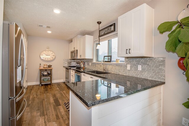 kitchen with kitchen peninsula, white cabinetry, hanging light fixtures, and appliances with stainless steel finishes