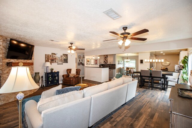 living room featuring a textured ceiling, ceiling fan, and dark wood-type flooring