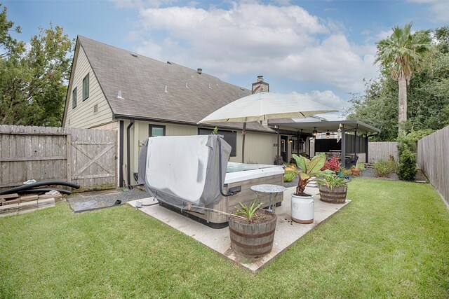 back of property featuring a yard, a hot tub, and a patio area