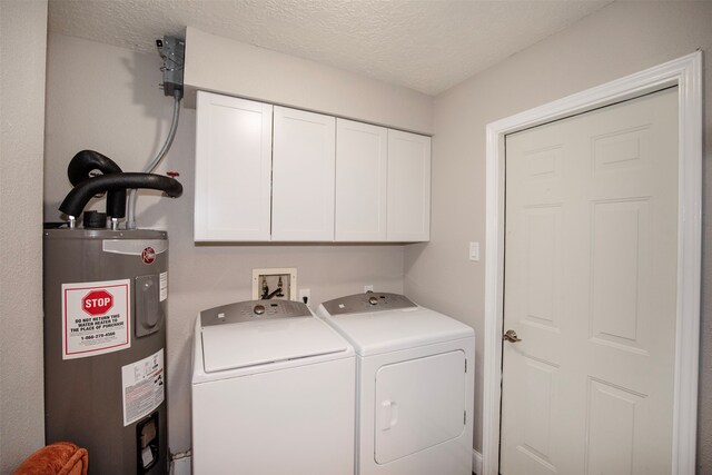 washroom featuring cabinets, washing machine and dryer, a textured ceiling, and water heater