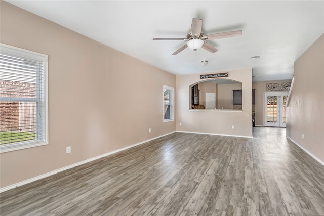 unfurnished living room with ceiling fan, dark wood-type flooring, and a healthy amount of sunlight