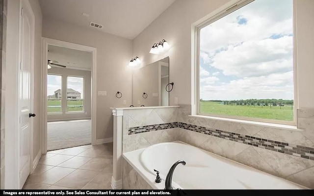 bathroom with a relaxing tiled tub, tile patterned flooring, ceiling fan, and a healthy amount of sunlight