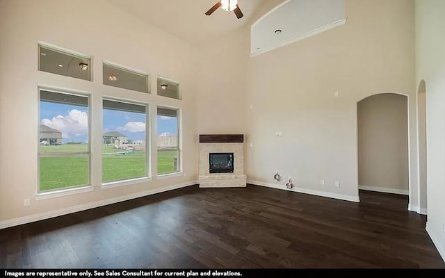 unfurnished living room with ceiling fan, a high ceiling, and dark hardwood / wood-style flooring