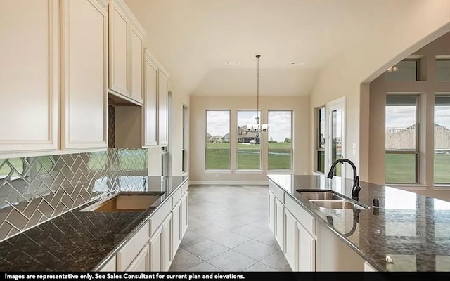 kitchen with hanging light fixtures, vaulted ceiling, sink, and a wealth of natural light