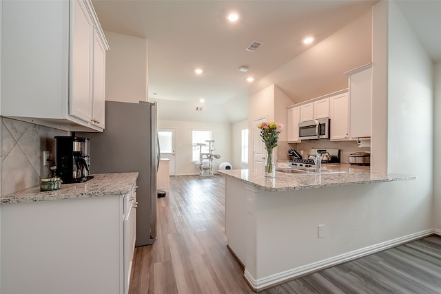 kitchen featuring light hardwood / wood-style flooring, white cabinets, light stone counters, and appliances with stainless steel finishes