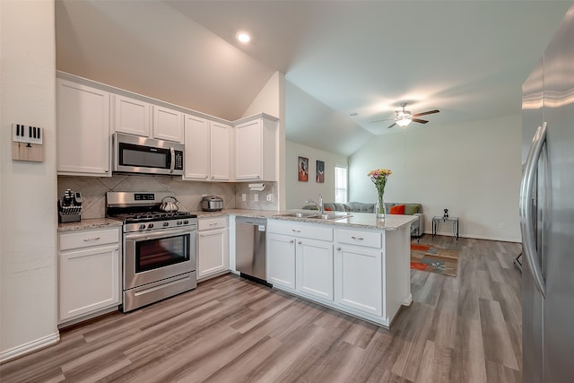 kitchen with appliances with stainless steel finishes, white cabinetry, kitchen peninsula, lofted ceiling, and ceiling fan