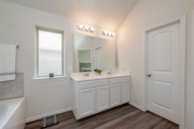 bathroom featuring lofted ceiling, vanity, a washtub, and hardwood / wood-style flooring