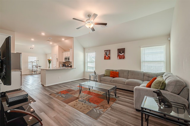 living room featuring light hardwood / wood-style flooring, lofted ceiling, and ceiling fan