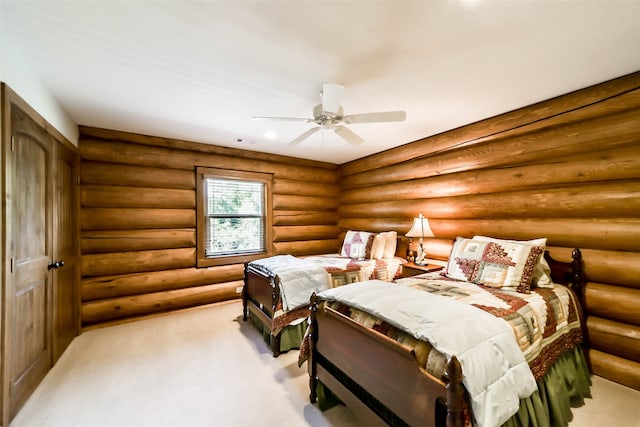 bedroom featuring light carpet, ceiling fan, and rustic walls