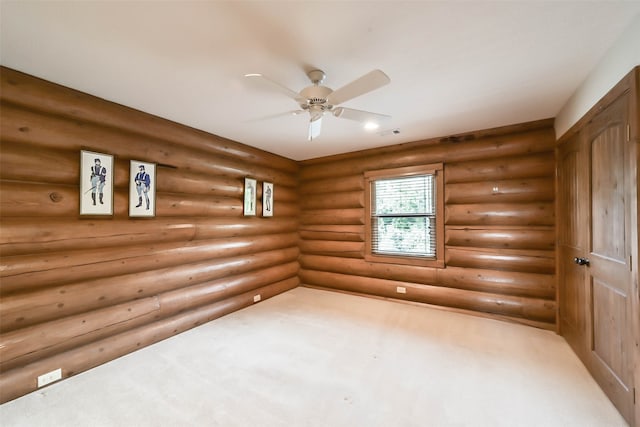 spare room featuring light carpet, rustic walls, and ceiling fan