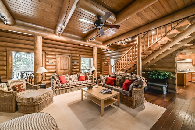 living room with ceiling fan, beamed ceiling, log walls, wooden ceiling, and dark hardwood / wood-style flooring