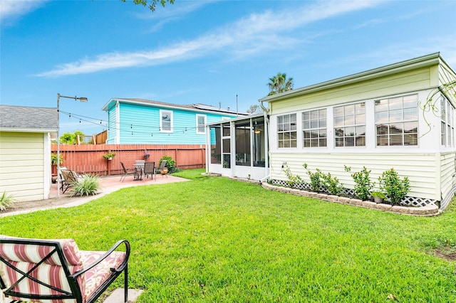 rear view of property featuring a lawn, a sunroom, and a patio