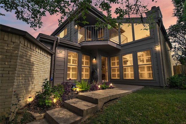 back house at dusk featuring a balcony