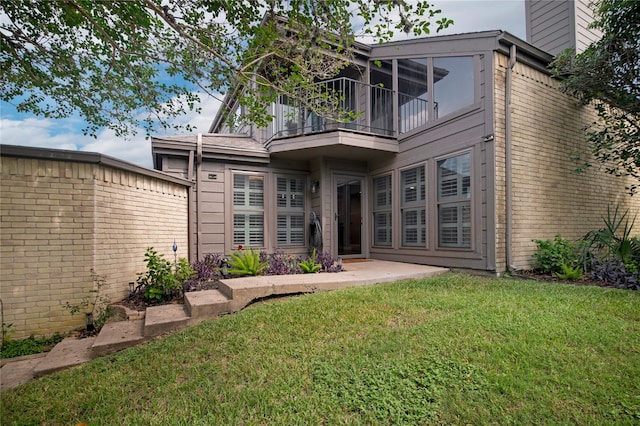 rear view of property featuring a lawn and a balcony